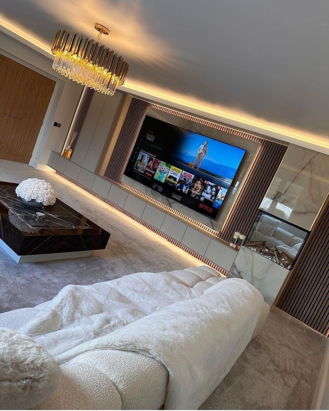Sala de estar planejada com painel de TV em mármore, ripado iluminado e lustre de cristal — Prime Line, Lourdes, Belo Horizonte